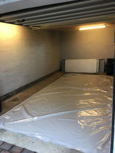 Åben garage med spildunderlag til bil